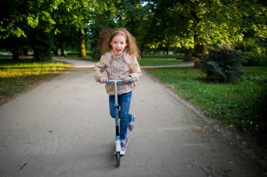 Bir scooter Şehir Parkı içinde 7-8 yaşındaki kız rides.