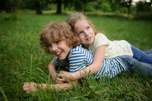 Hermano y hermana juegan en un césped verde — Foto de Stock