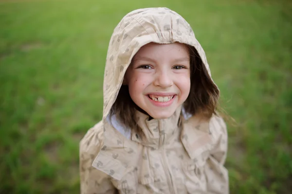 De belachelijk kleine meisje kijkt in een camera en glimlach. — Stockfoto