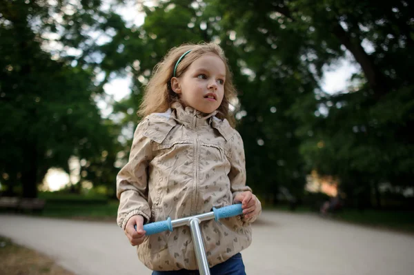 Девушка 7-8 лет со скутером в городском парке . — стоковое фото
