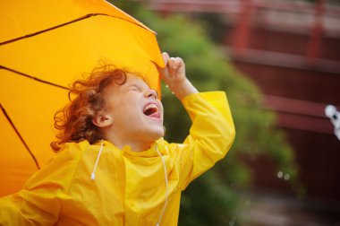 Çiseleyen yağmur ve dil küçük çocuk tribünde yağmur damlaları yakalar.