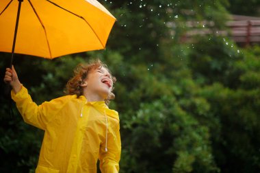 Sarı bir şemsiye ile çocuk yakalar dil yağmur damlaları.