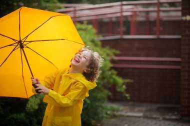 Yağmur sarı bir şemsiye çocukla sevinir.