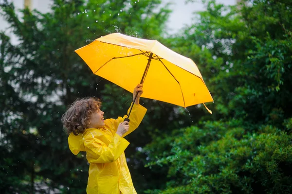 Laddie with a bright yellow umbrella in the warm summer rain. — Stock Photo, Image