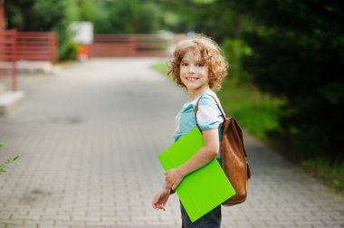İlköğretim Okulu öğrencisi standı yarım dönüş içinde fotoğraf makinesi ve sevinçle gülümsüyor