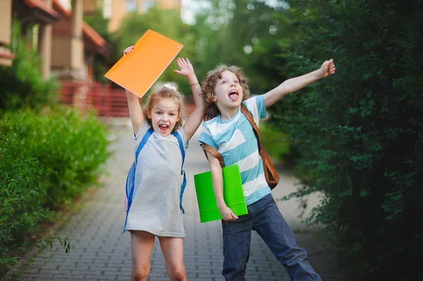 Niño y niña se alegran de la terminación del año académico . — Foto de Stock