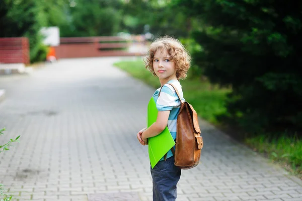 Skolpojke går till skolan med en skolväska bakom axlar. — Stockfoto