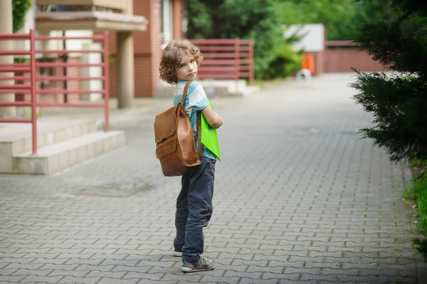 Liten skolpojke stå på en skolgård. — Stockfoto