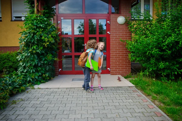 Scholier met schoolmeisje staan op de deuren van de school en over iets mutter. — Stockfoto