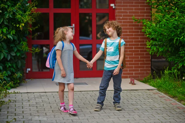 Мальчик и девочка идут в школу, взявшись за руки . — стоковое фото