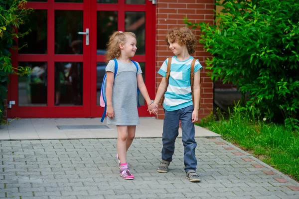 Ragazzo e ragazza vanno a scuola avendo unito le mani . — Foto Stock