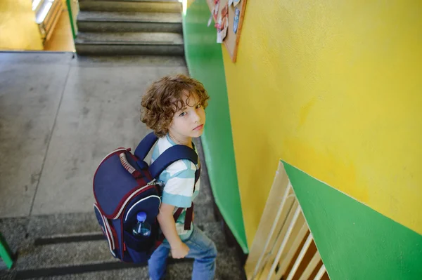 Liten skolpojke stående på trappan till skolan trappan. — Stockfoto