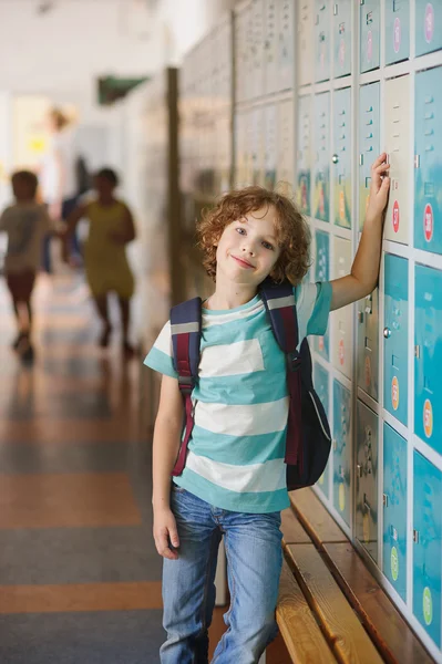 Kleiner Schüler steht neben Schließfächern im Schulflur — Stockfoto