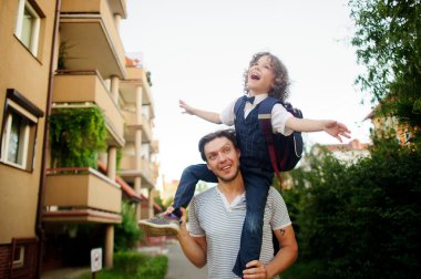 Babasının omuzlarında oturan küçük öğrenci.