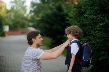 The father sees off the son-first-grader in school. clipart