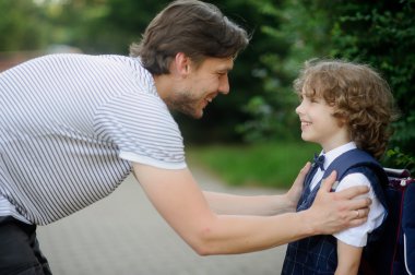 Father with his son-first-graders in the school yard. clipart