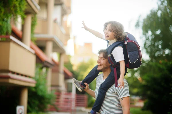 Weinig leerling zittend op de schouders van zijn vader. — Stockfoto