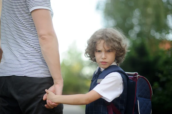 Отец ведет за руку в школе маленького школьника — стоковое фото