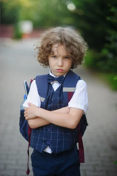 Kleiner Schüler steht mit wütendem Gesichtsausdruck auf dem Schulhof . — Stockfoto