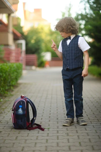 Μικρό σγουρά μαλλιά μαθητής θέσει σακίδιο του στο πεζοδρόμιο. — Φωτογραφία Αρχείου