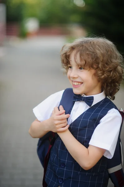 Söt liten skolpojke står på trottoaren. — Stockfoto