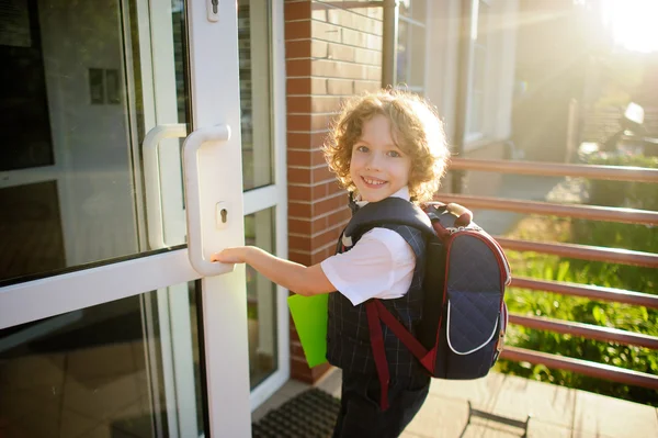 Маленький странный школьник открывает школьную дверь — стоковое фото