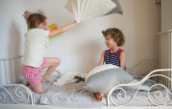 Brother and sister have arranged fight by pillows on a bed in bedroom. — Stock Photo, Image