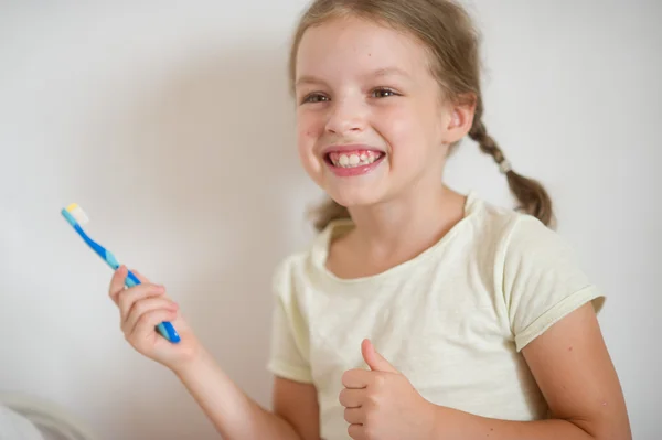 Nettes fröhliches Mädchen putzt ein Gebiss. — Stockfoto