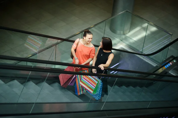 Dwie młode kobiety na schodniku w centrum handlowym. — Zdjęcie stockowe