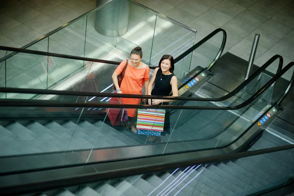 Dwie ciemnowłosy młoda dziewczyna na schody ruchome w centrum handlowym. — Zdjęcie stockowe