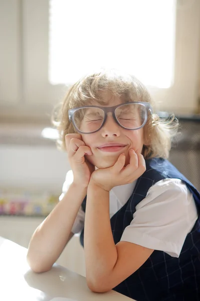 Lustiger kleiner Schuljunge mit riesengroßer Brille ist in Träumerei verfallen. — Stockfoto