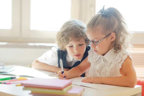 Zwei kleine Klassenkameraden, Junge und Mädchen, sitzen am gleichen Schreibtisch — Stockfoto