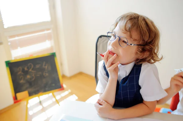 Netter kleiner Schüler mit Brille ist in Träumerei verfallen. — Stockfoto