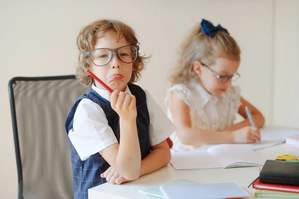 Pequeños alumnos divertidos se sientan en un escritorio . —  Fotos de Stock