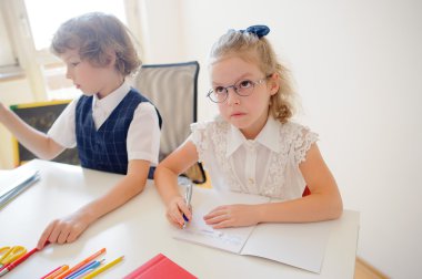 İki küçük bir ilköğretim okulu öğrencileri masa başında oturmak.