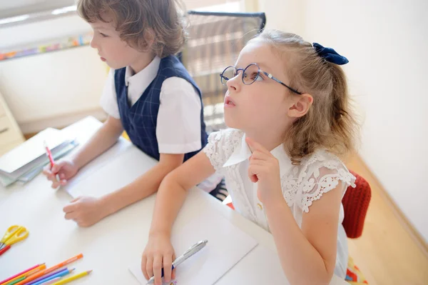 Zwei kleine Schüler einer Grundschule sitzen am Schreibtisch. — Stockfoto