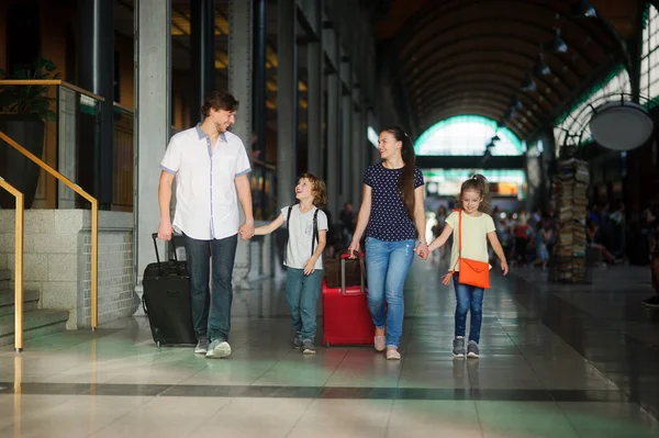 Padres jóvenes con hija e hijo pasan por la sala de espera de la estación . — Foto de Stock