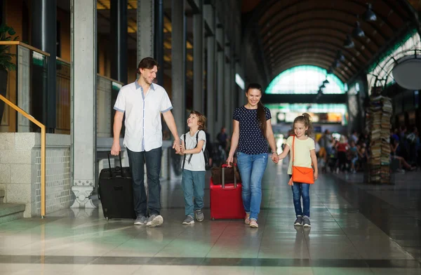 Young parents with daughter and son go through the waiting room at the station. — Zdjęcie stockowe