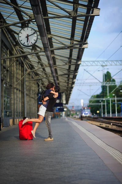 The young pair stand having embraced on platform under clock. — Stock Photo, Image
