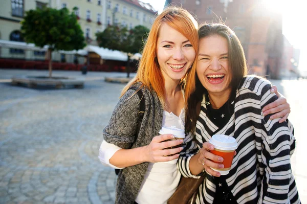 Twee schattige jonge vrouwen staan op het plein van de prachtige Europese stad. — Stockfoto