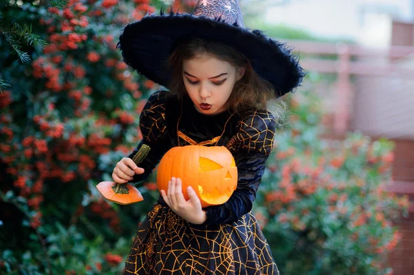 Mooi meisje van 8-9 jaar in pak voor Halloween met een pompoen in de handen. — Stockfoto
