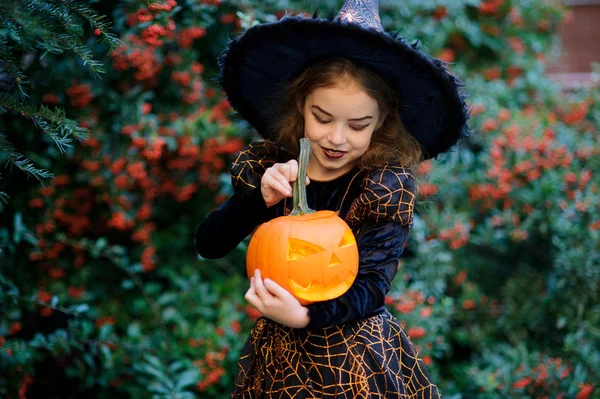 Niedliches Mädchen von 8-9 Jahren im Anzug zu Halloween mit einem Kürbis in den Händen. — Stockfoto