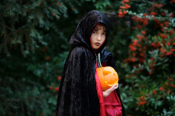 Menino da idade escolar primária em um manto preto-vermelho retrata o feiticeiro do mal . — Fotografia de Stock