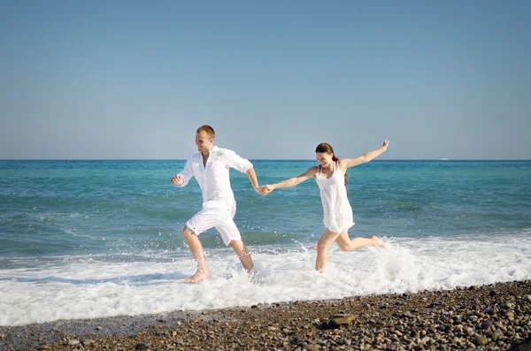Jovem casal correndo na praia nas ondas — Fotografia de Stock