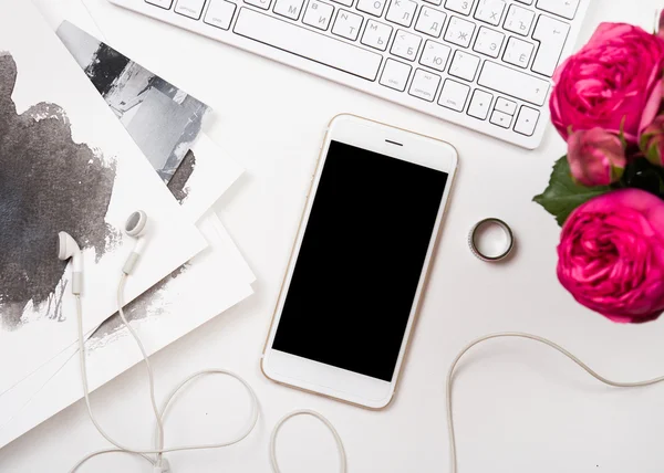 Smartphone, Computertastatur und festliche rosa Blumen auf weißer Lasche — Stockfoto