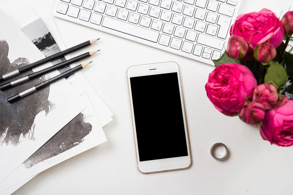 Smartphone, számítógép-billentyűzet és fesh rózsaszín virágok fehér lap — Stock Fotó