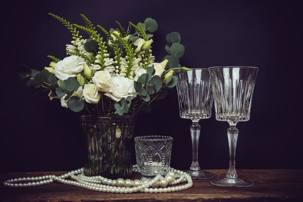 Ramo de flores blancas, perlas y copas de vino en un blac —  Fotos de Stock