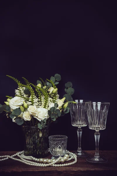 Boeket van witte bloemen, parel kralen en wijnglazen op een zwart — Stockfoto