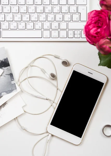 Smartphone, Computertastatur und festliche rosa Blumen auf weißer Lasche — Stockfoto