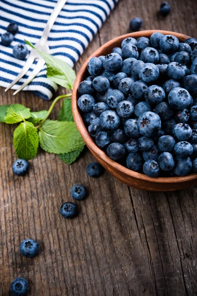 Full bowl of fresh ripe blueberries on old wooden board — Stock Photo, Image